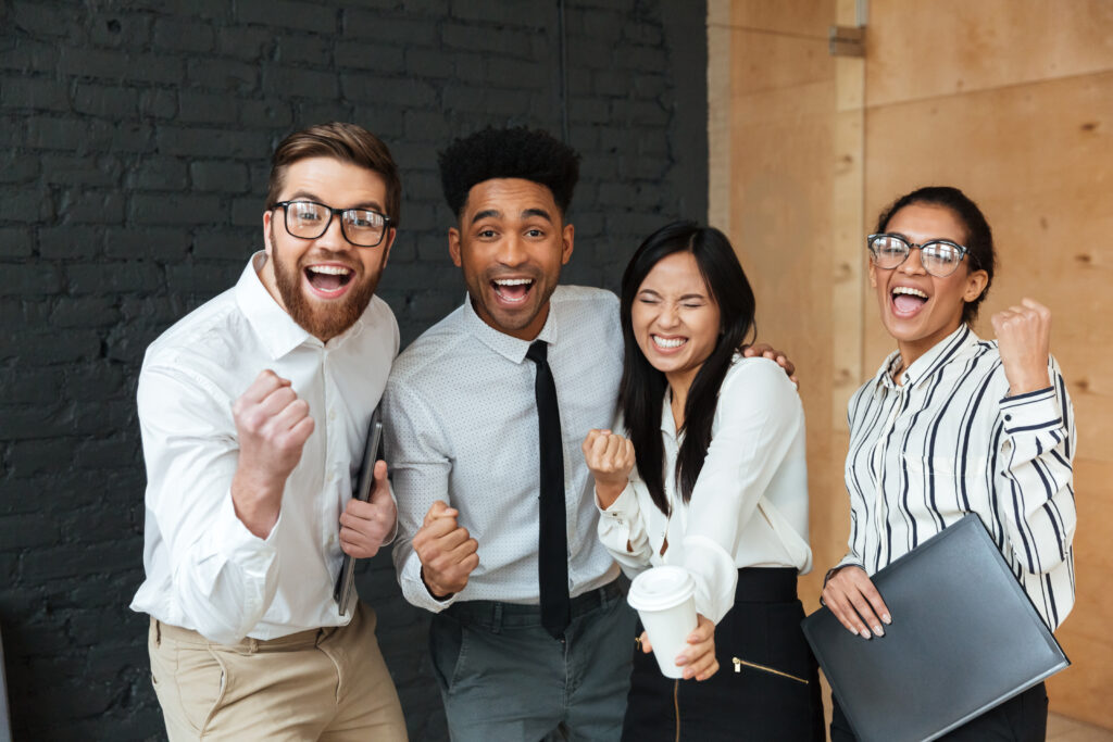 happy and excited colleagues making winner gesture