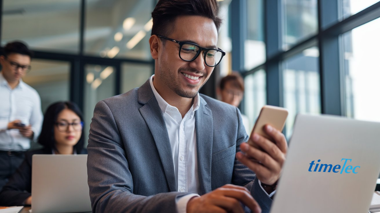 Malaysian businessman using a smartphone for employee leave management in a modern office.