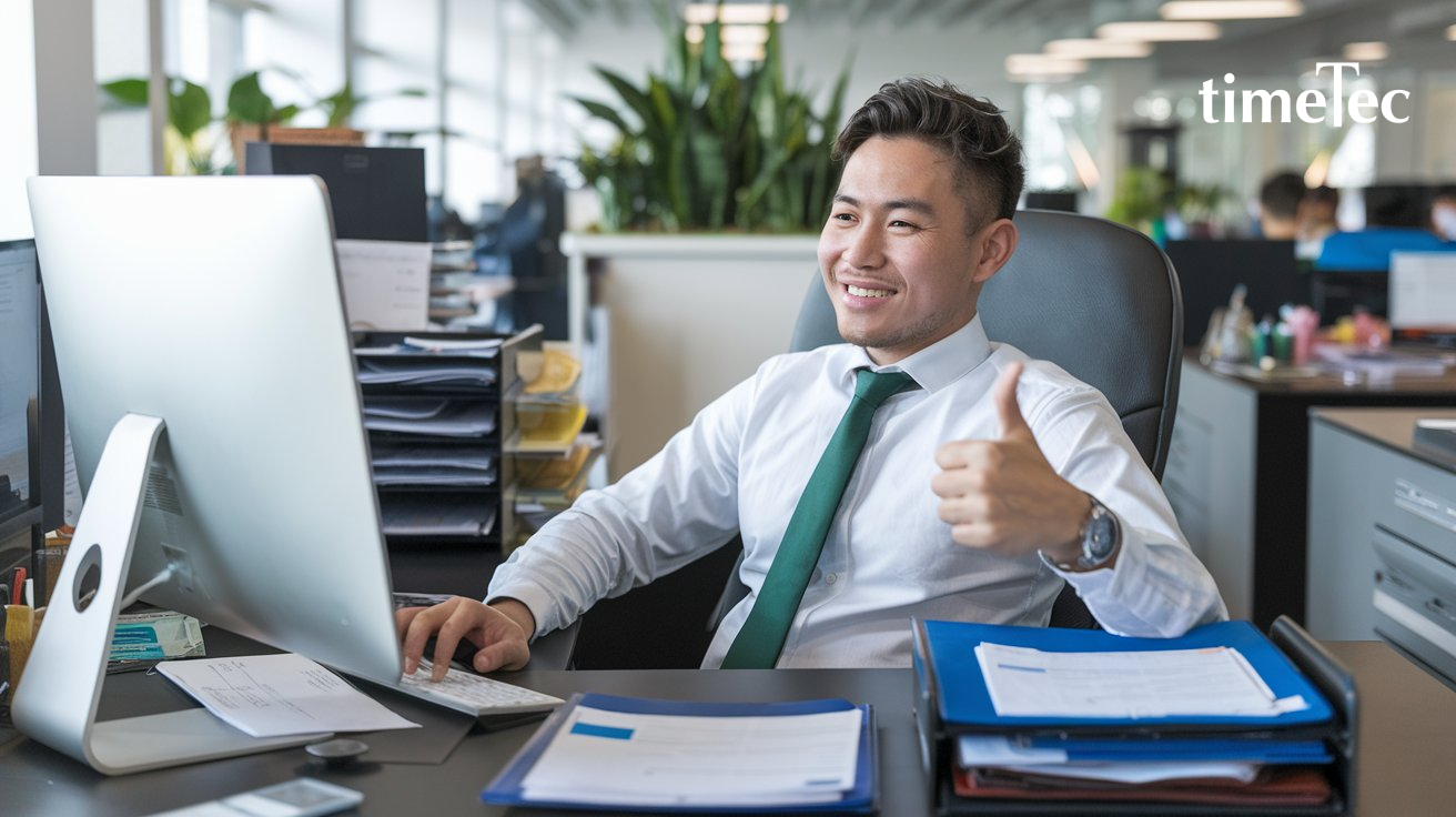 Male employee giving a thumbs-up while working on payroll management in a modern office.