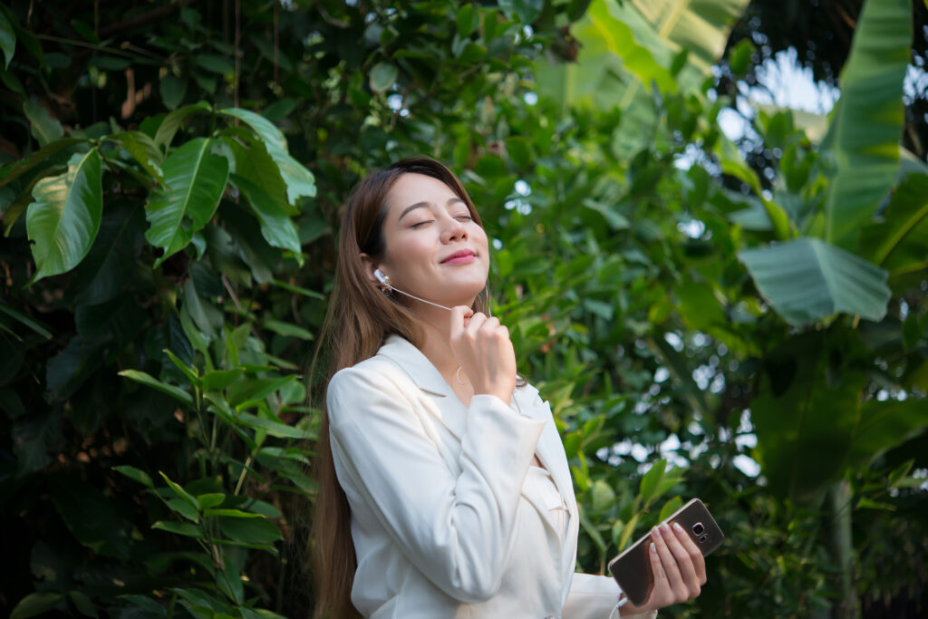 Woman enjoying nature with earbuds, representing environmental impact of digital claims processing