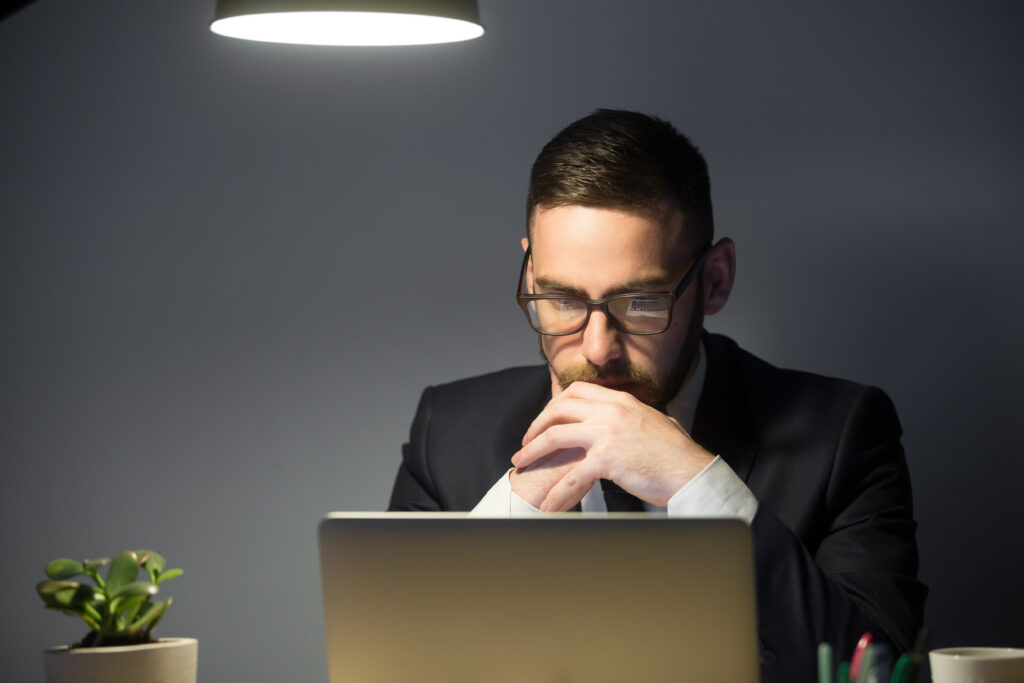 Businessman contemplating payroll compliance strategy while working on a laptop