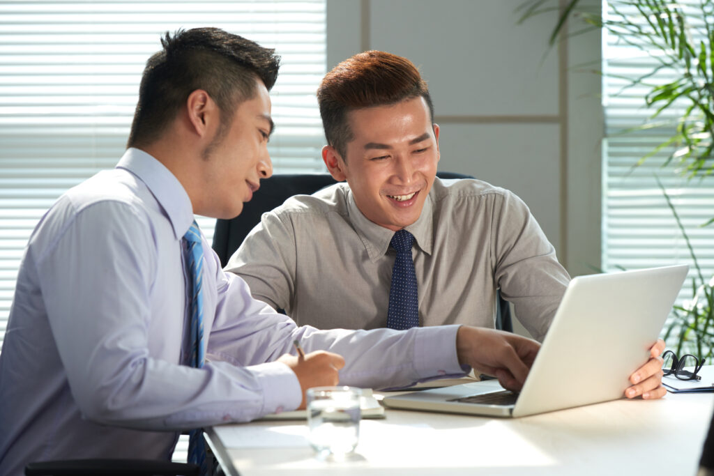 Two coworkers in a meeting discussing employee leave policies with a laptop.