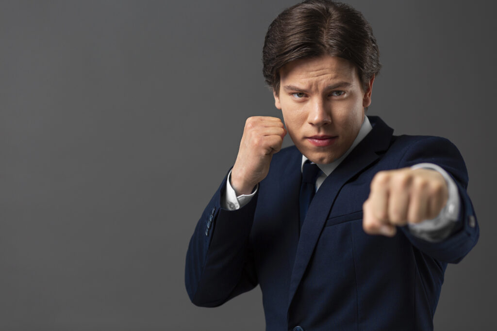 Confident businessman in a suit posing with a fighting stance, symbolizing overcoming challenges in claims management.