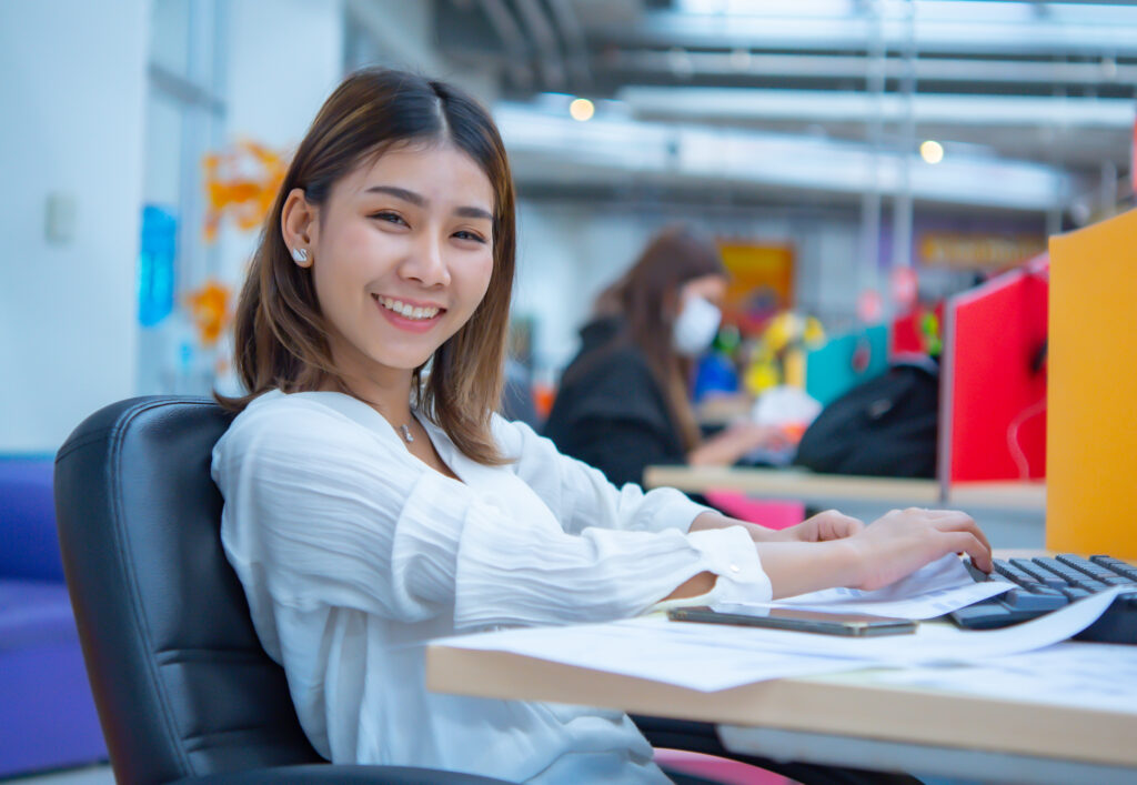 Smiling businesswoman working on a laptop in a modern office setting.