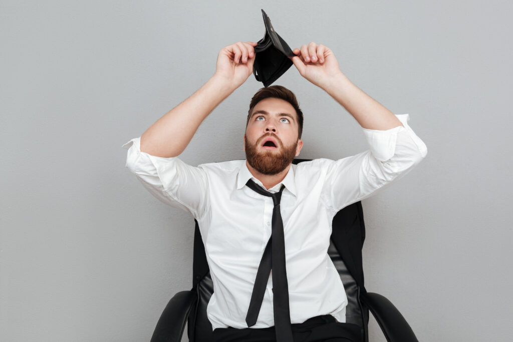 Frustrated man in a white shirt holding an empty wallet symbolizing the sinking funds gone. 