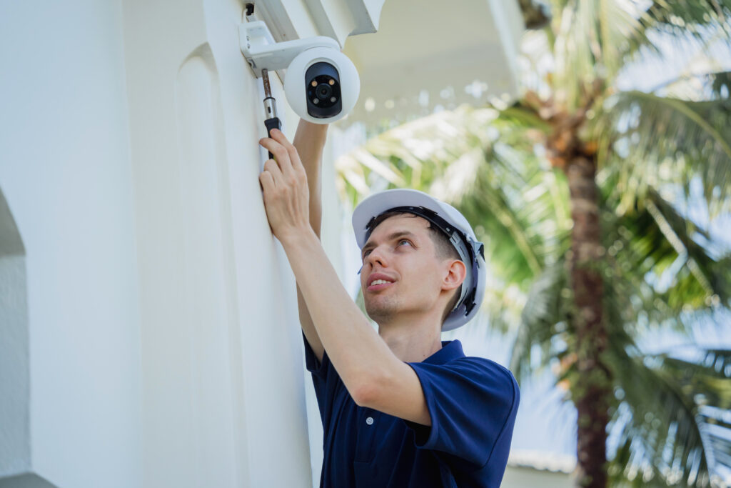 Technician installing a CCTV camera on the facade of a residential building.