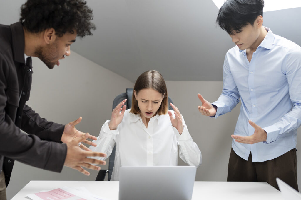 A workplace scene depicting conflict resolution, with two individuals addressing a disagreement while another looks distressed.