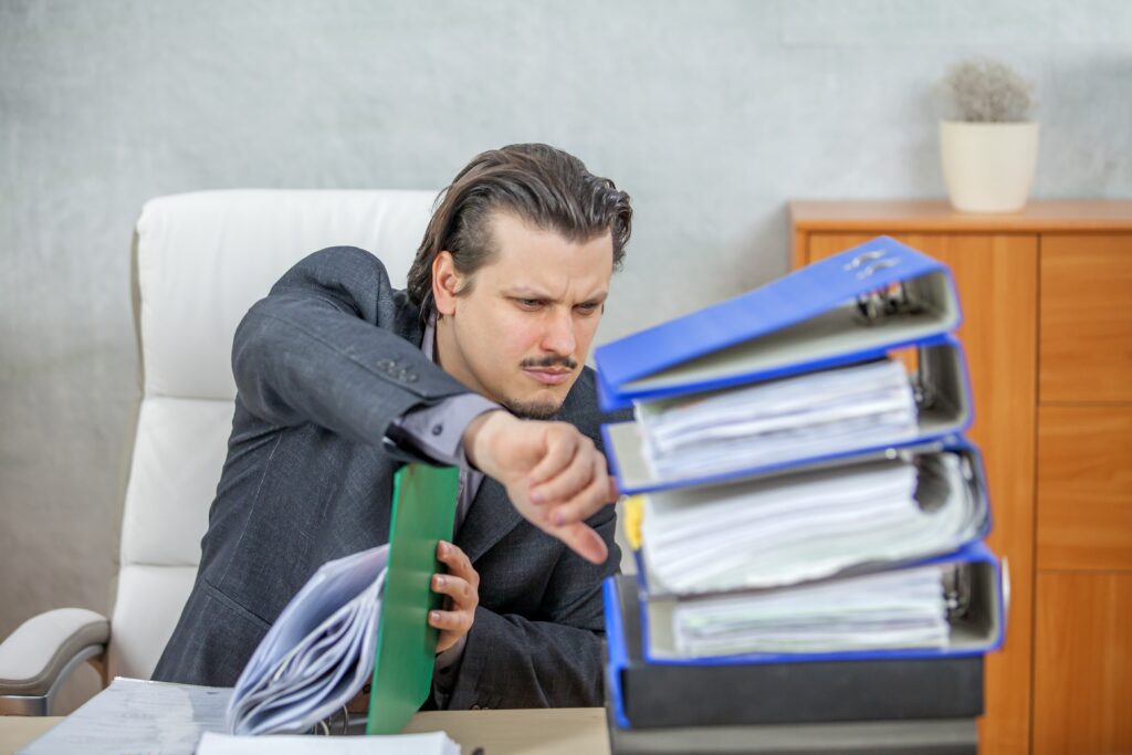 A businessman overwhelmed by paperwork, emphasizing the need for E-Forms in Residential Management to reduce errors.