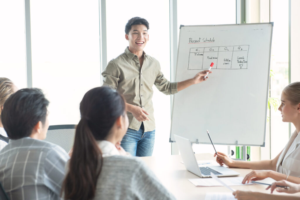 A man presenting financial and management strategies on a whiteboard during a community meeting.