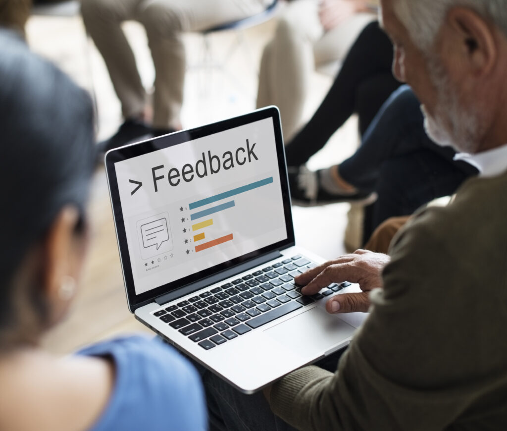 Man analyzing feedback data on a laptop in a meeting setting.