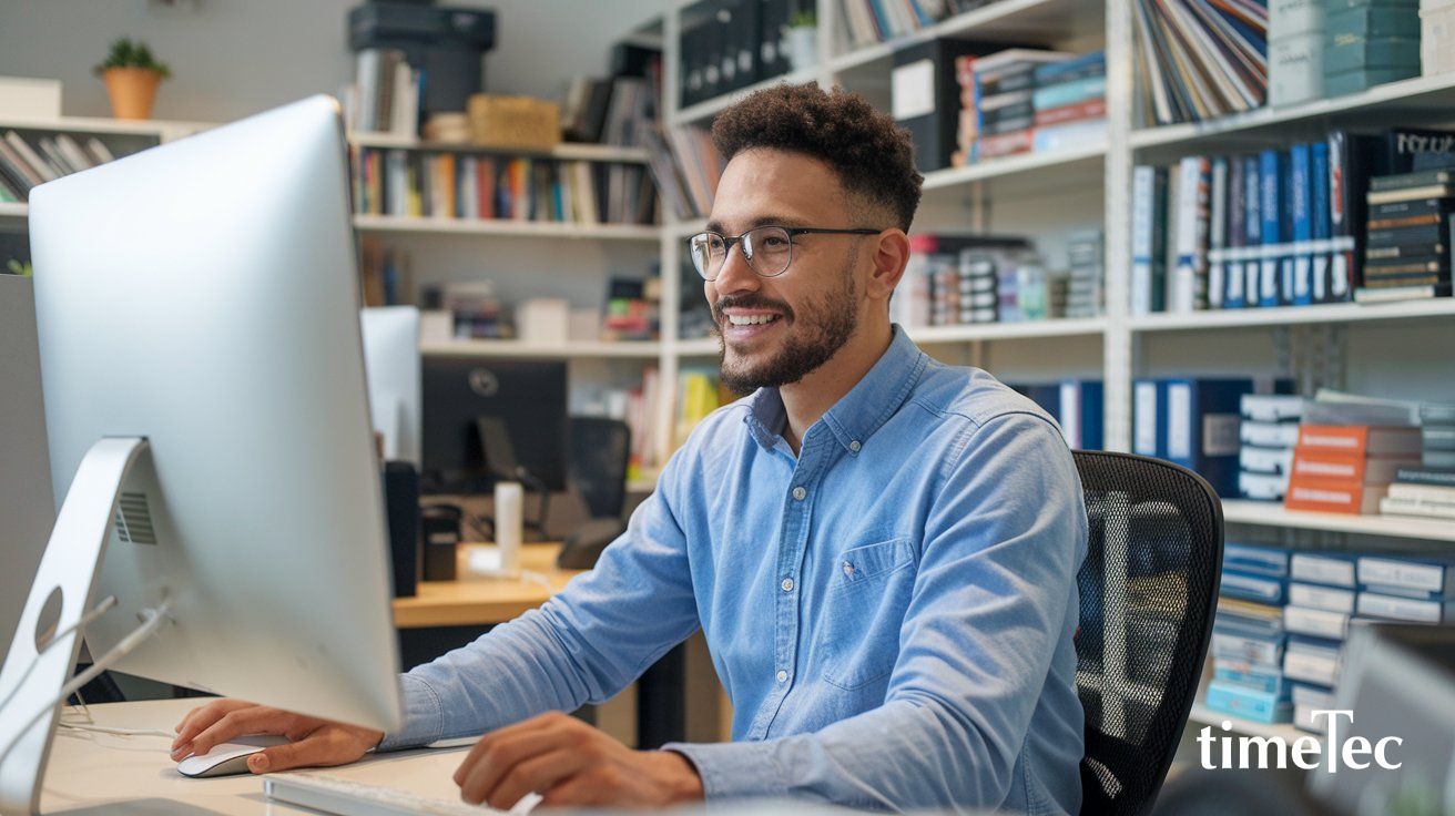 Smiling employee working at a computer while efficiently handling unplanned leave.