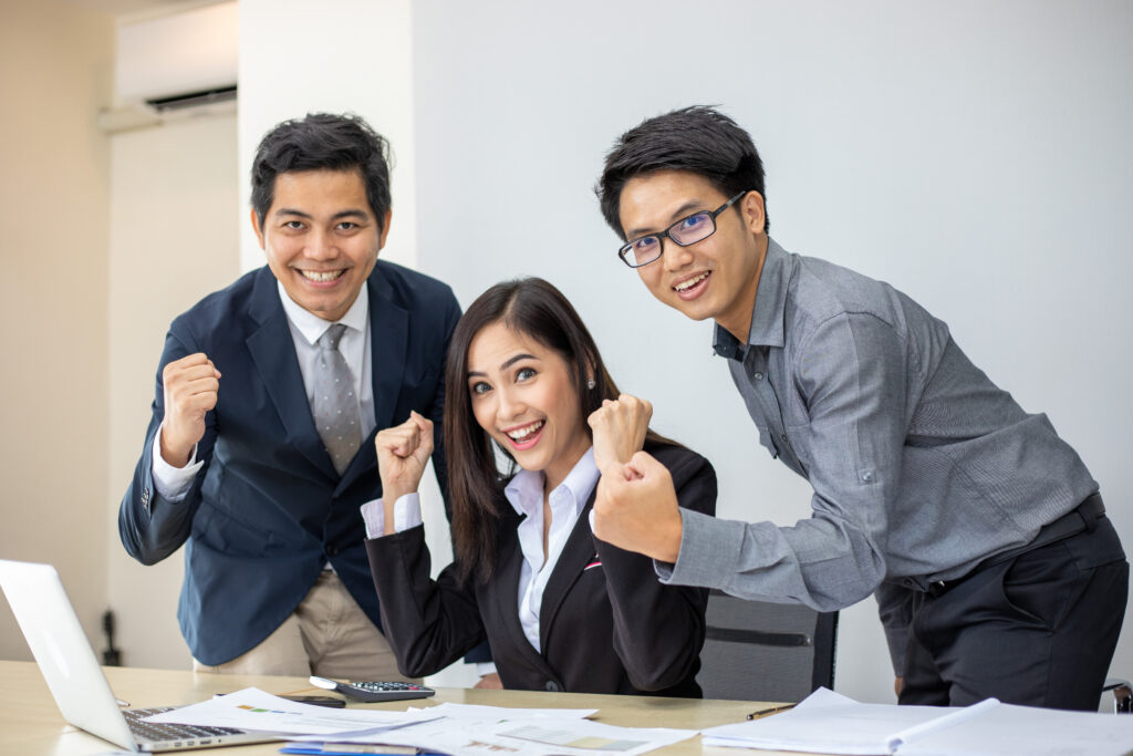 A team celebrating success, illustrating the benefits of HRMS for remote and hybrid workforces in time and attendance tracking.