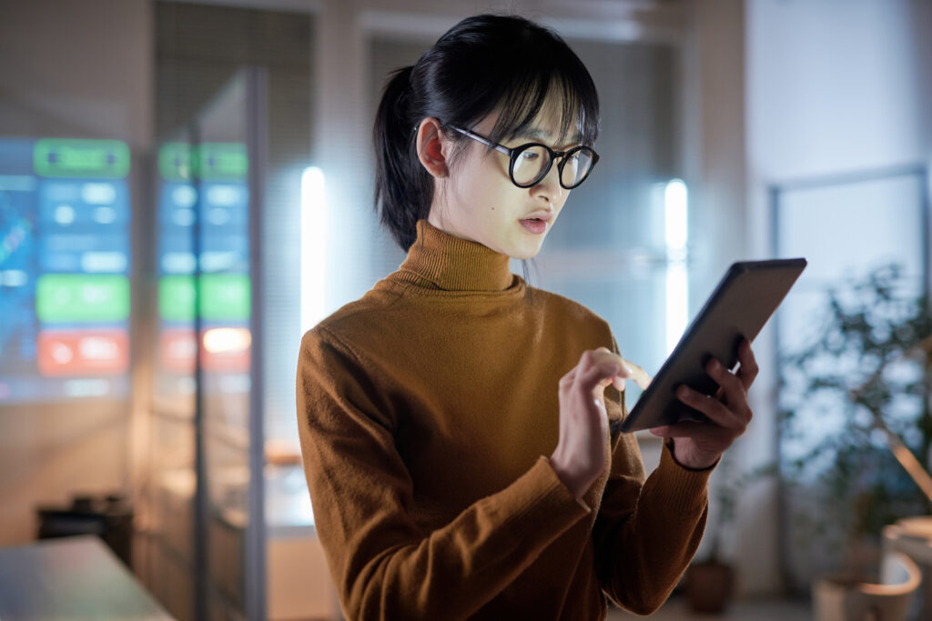 A businesswoman analyzing data on a tablet, illustrating the power of HRMS for remote and hybrid workforces in data-driven decision-making.