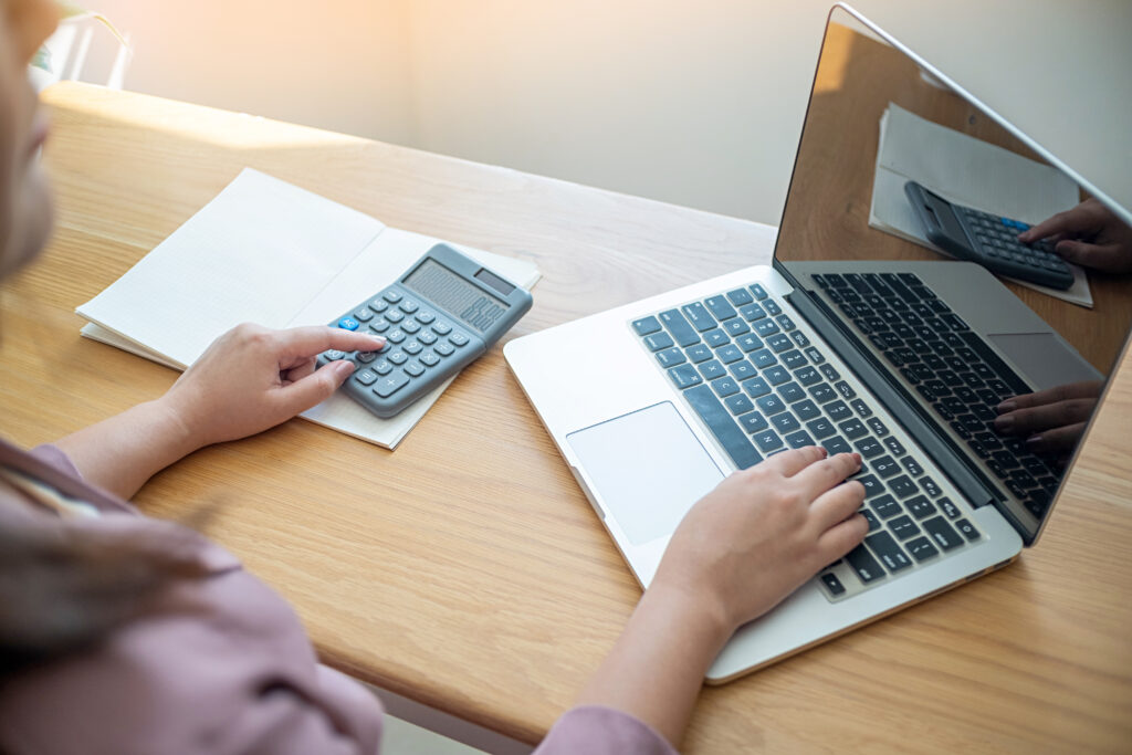 Woman using a laptop and calculator to automate Residential Monthly Payment Management.