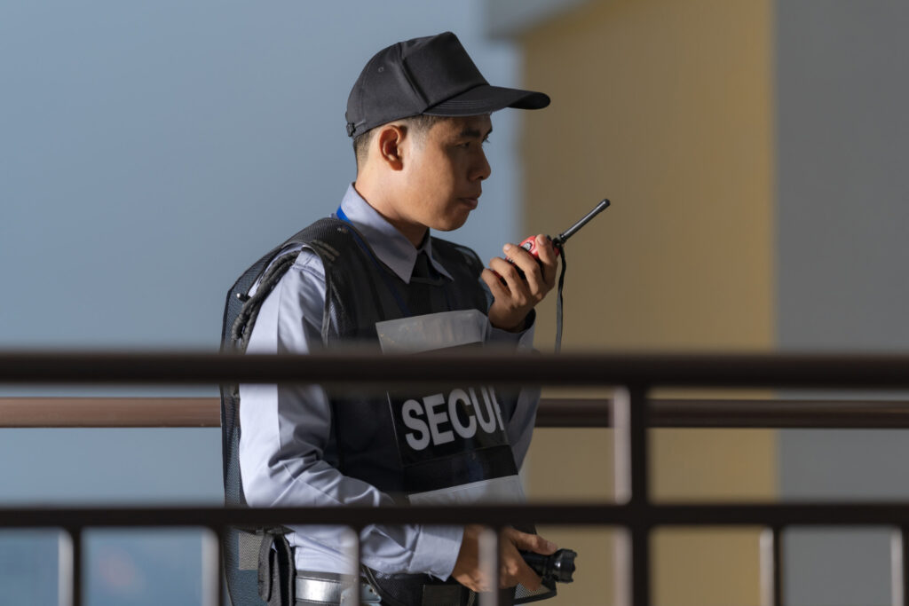 A security guard using a walkie-talkie to verify a visitor’s identity, demonstrating the role of OCR in Visitor Management for enhanced security.