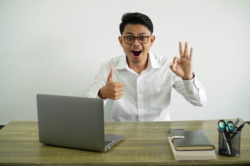 Man at a desk giving an OK sign, representing confidence in Residential E-Billing Solutions automation.