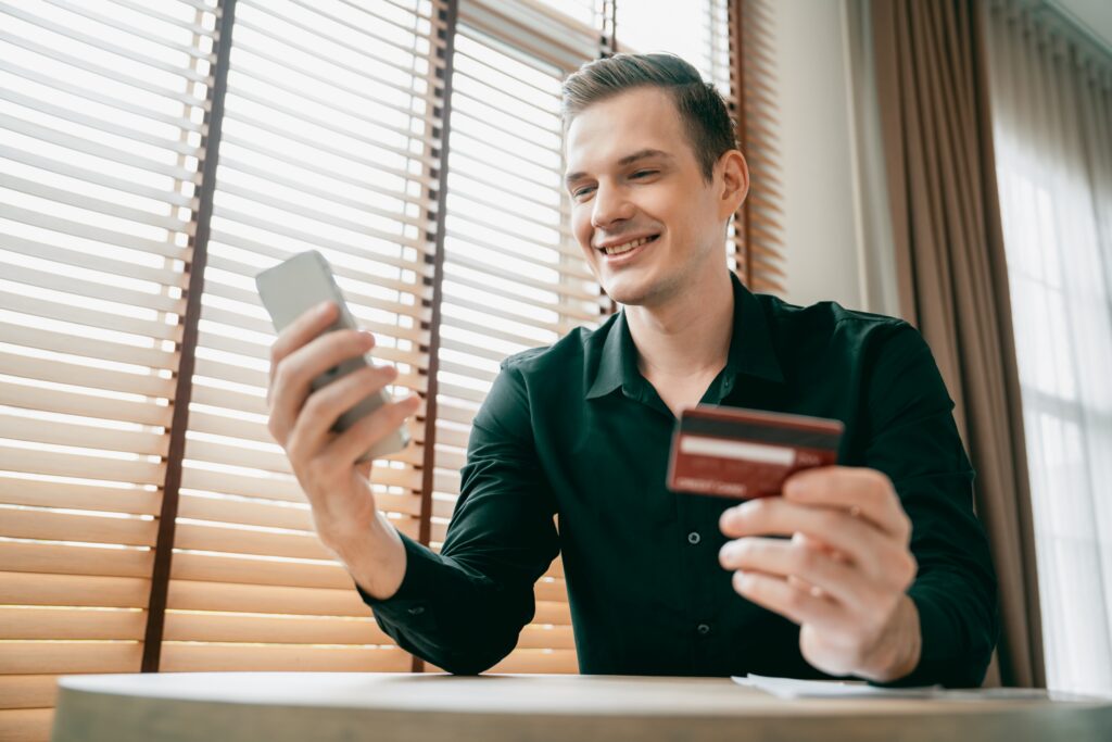 Man using a smartphone and credit card for Residential Monthly Payment Management.