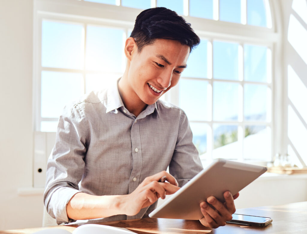 A man using a tablet to manage facility bookings with Facility Booking Technology in a bright office.